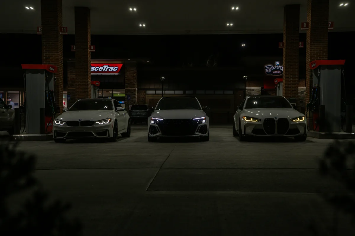 Three performance cars facing forward beneath night lights